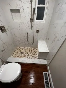 Curbless walk-in shower with built-in bench, niche and pebble tile floor