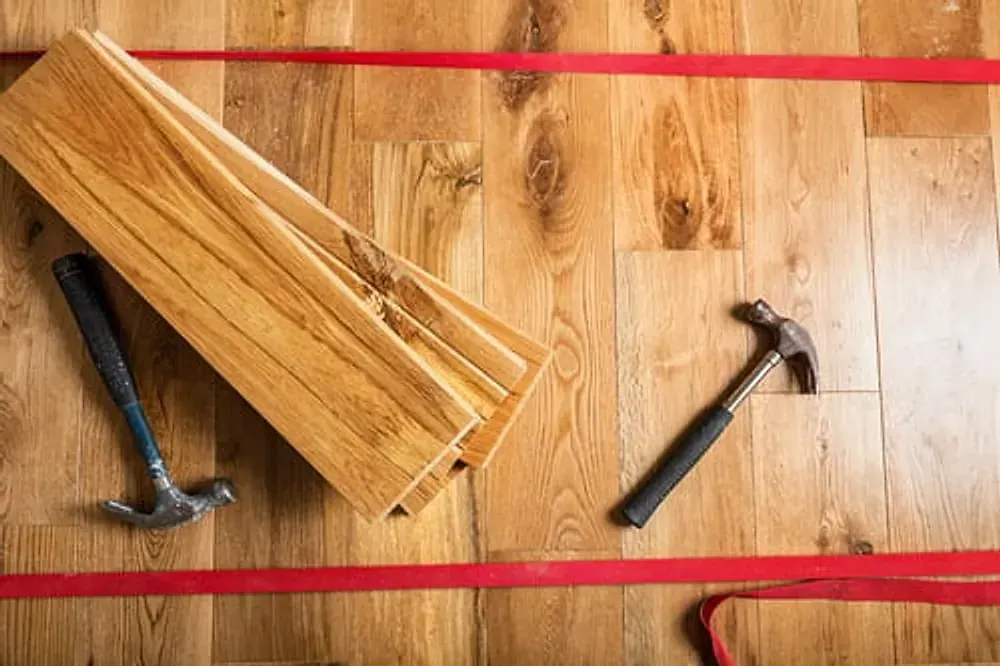 Flooring planks and hammers laid out on a wood subfloor ready for installation day