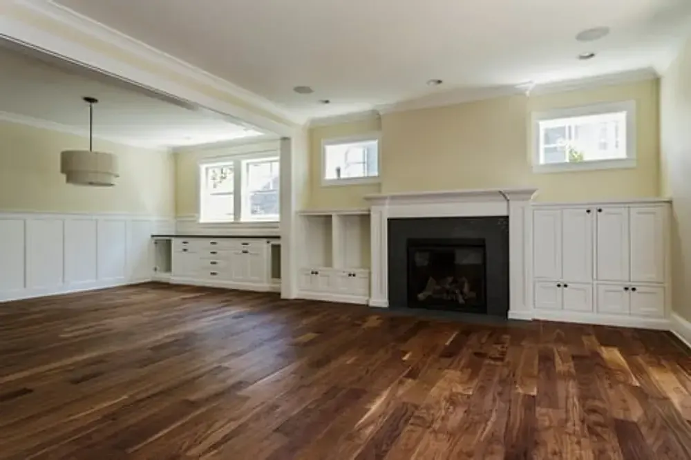 Empty living room with newly installed engineered hardwood flooring and white trim